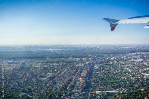 Taking off from Otopeni airport; flying over residential neighborhoods, Bucharest skyline in the background; Romania