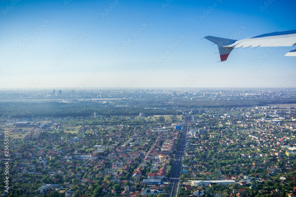 Taking off from Otopeni airport; flying over residential neighborhoods, Bucharest skyline in the background; Romania